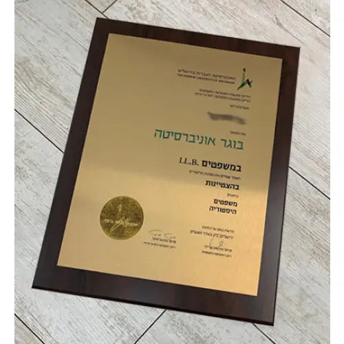 תעודת עורך דין במסגרת עץ כהה עם נייר זהב וטקסט בעברית וחותם מוטבע